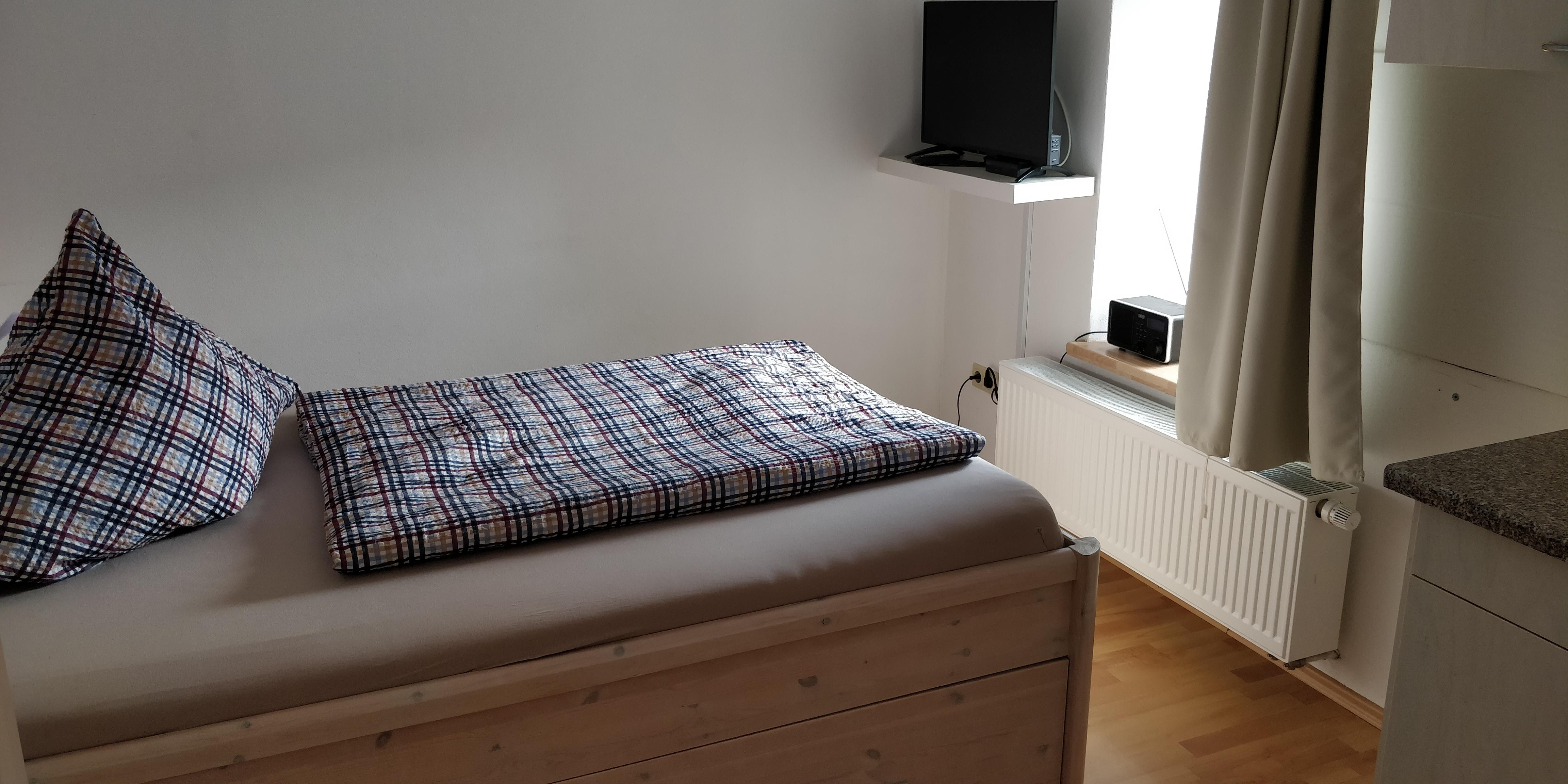 Einzelzimmer mit Bett und Fenster